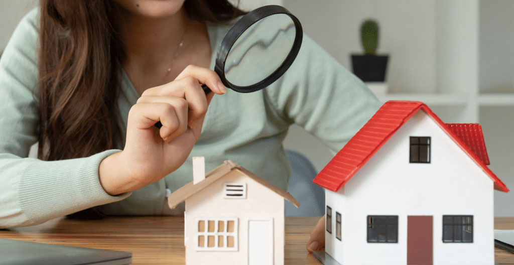 Professionnel de l'immobilier analysant des données de marché et transactions récentes sur son ordinateur dans un bureau contemporain avec plans cadastraux